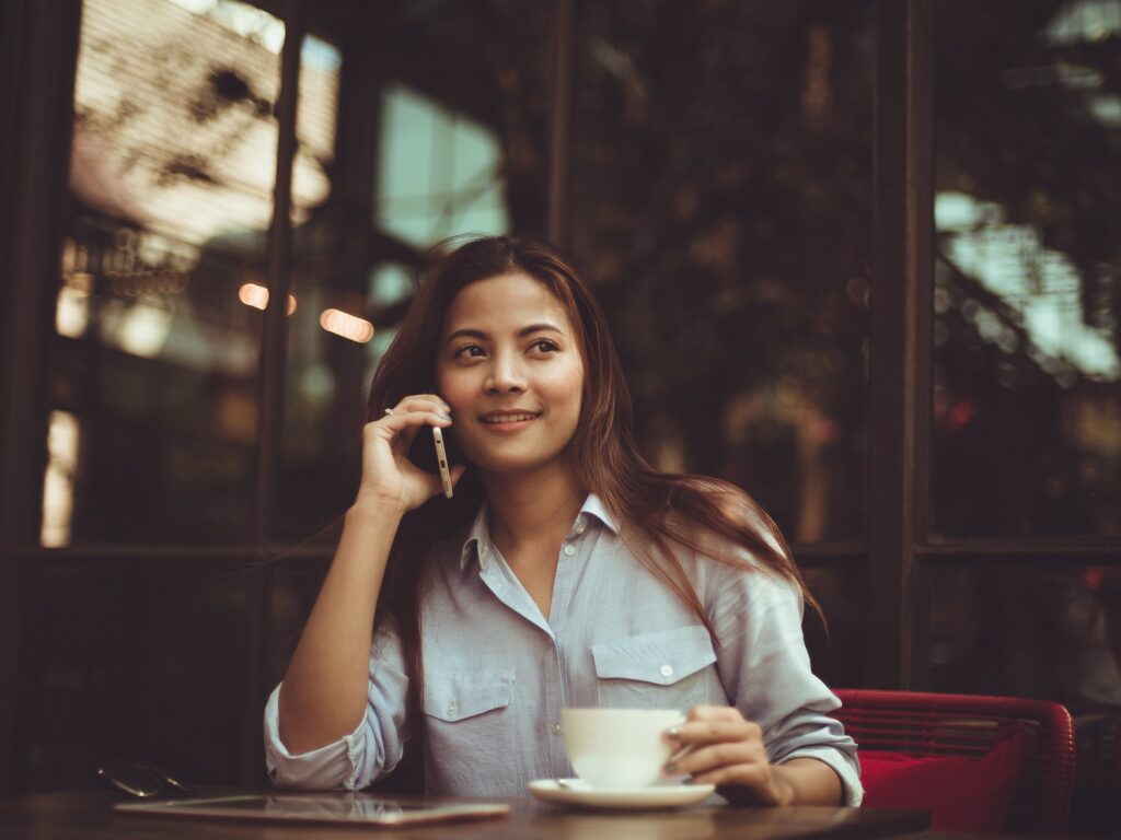Woman on the phone while enjoying a cofee